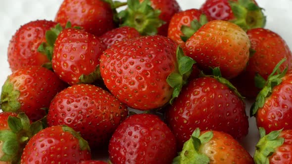 4K Beautiful ripe red strawberry rotates on a plate. Slow rotation of strawberries close-up top view