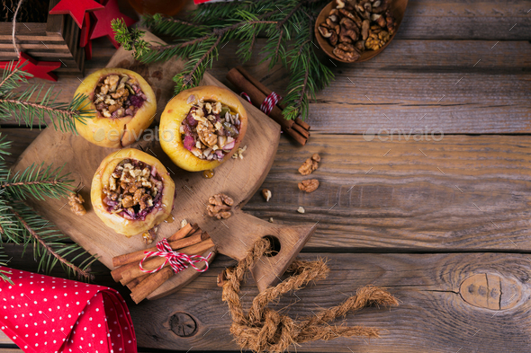 Baked apples stuffed with berries, walnuts and honey on a wooden cutting board. - Stock Photo - Images