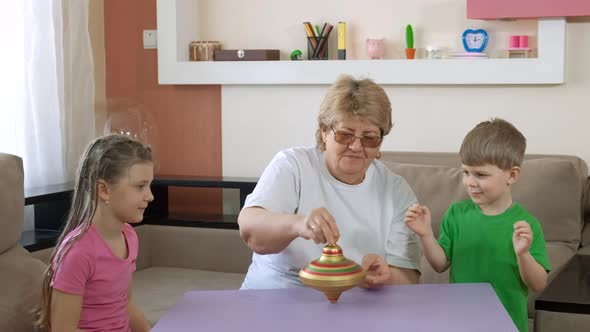 Grandma Teaches the Children How to Turn an Old Toy Spinning Top in the Room