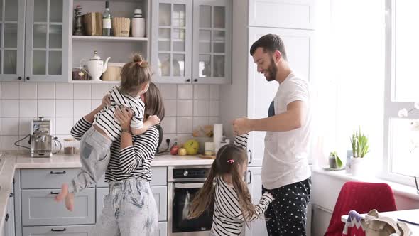 Young Family with Two Daughters are Dancing on the Kitchen alt
