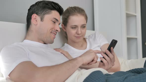 Couple Using One Smartphone in Bed alt