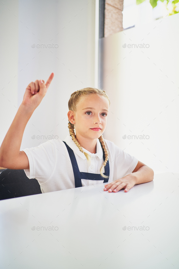 Little spanish school girl raising hand in class to intervene