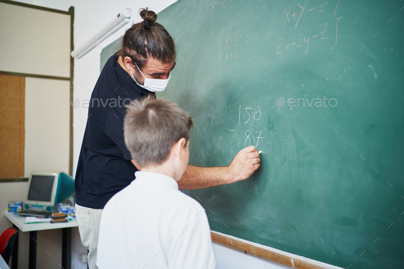 Spanish teacher wearing mask shows to student kid how to make exercise