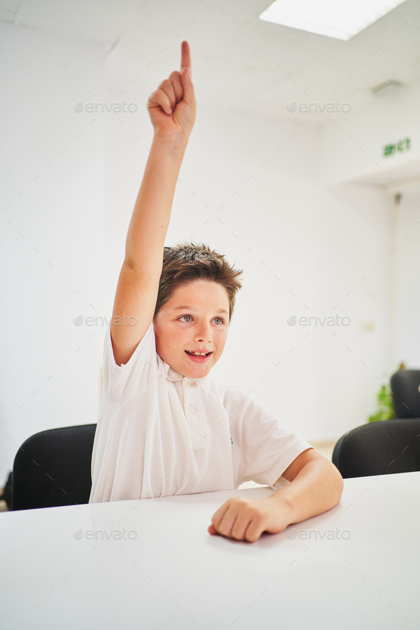 Little spanish school boy raising hand in class to intervene