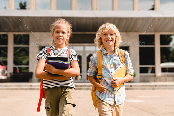 Two little pupils classmates schoolchildren students going back home ...