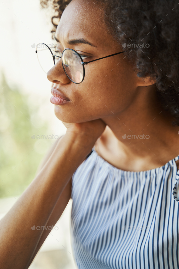 Low-spirited female in trendy circle eyeglasses staring into the distance