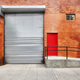 Empty street with brick wall building with automatic rolling shutter. - PhotoDune Item for Sale