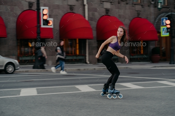 Slim sporty young woman uses rollerskates as mode of transportation in city - Stock Photo - Images