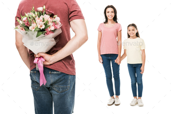 partial view of man with bouquet of flowers behind back and smiling family isolated on white