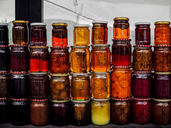 stacks of jars with honey and pickled fruits on market at armenia