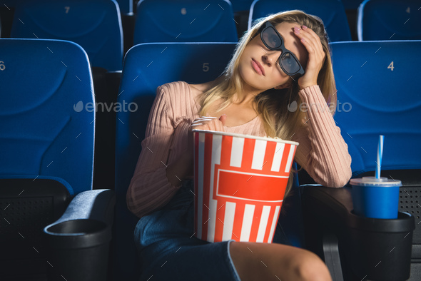 portrait of young woman in 3d glasses with popcorn watching film alone in cinema