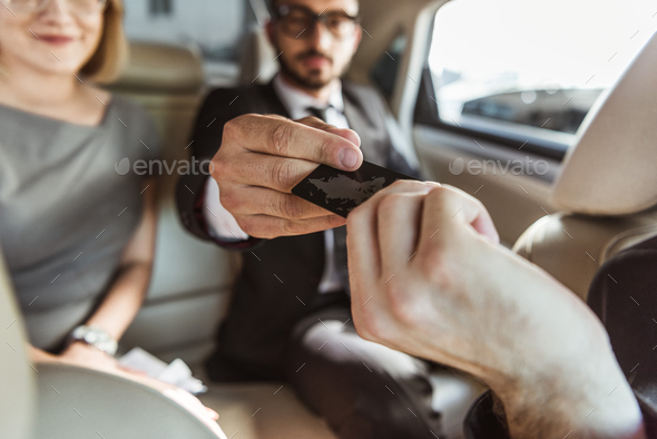 businessman giving credit card to driver to pay for taxi