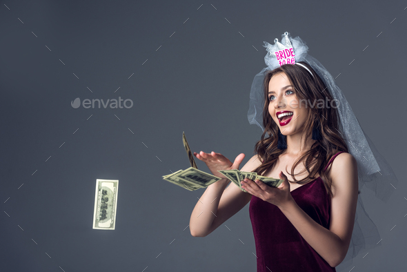 beautiful future bride in veil for bachelorette party throwing money away isolated on grey