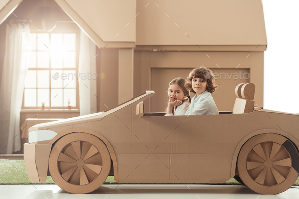 side view of happy little kids riding cardboard car