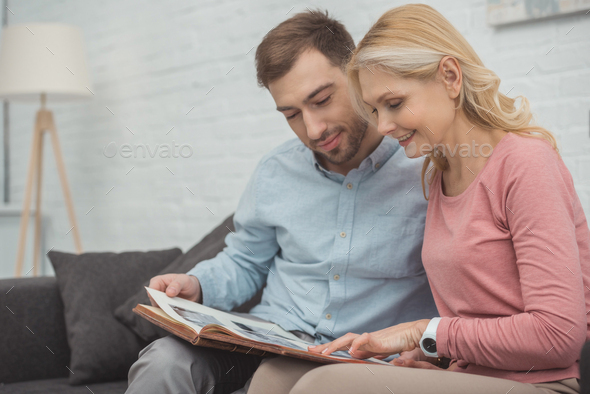 happy family looking at photos in photo album together at home