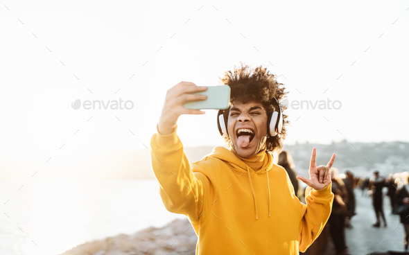 Young Afro man taking self video while listening music with wireless headphones