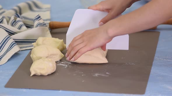 Female hands cut with a scrapper a kneaded dough