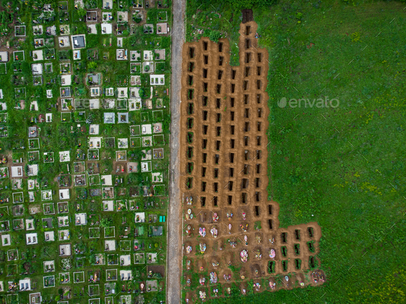 Open empty graves among the green lawn, aerial drone view of emty tombs.