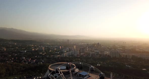 Ferris wheel at sunset overlooking the city and mountains alt
