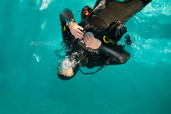 Male diver in scuba gear poses in pool, top view