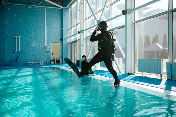 Diver in scuba gear jumps into the pool, diving