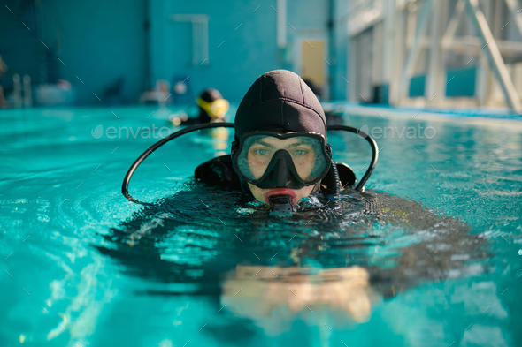 Male diver in scuba gear and mask poses in pool
