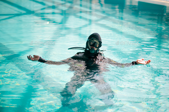 Male diver in scuba gear poses in pool, diving