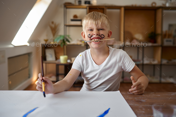 Little boy drawing with gouache on his face - Stock Photo - Images