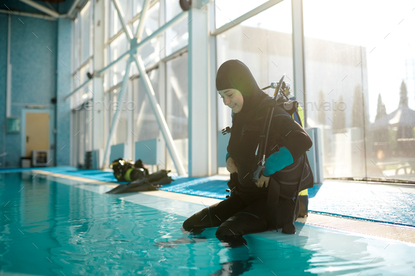 Male diver in scuba suit sitting at the poolside - Stock Photo - Images
