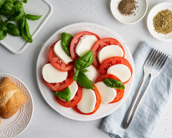 Classic italian caprese appetizer with tomatoes, mozzarella, basil, bread and oregano