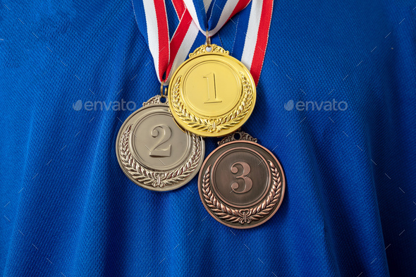 Gold, silver and bronze medals set on blue shirt background. Sports athletes winners prize
