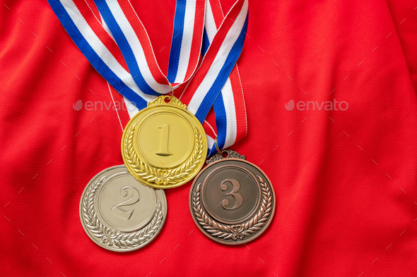 Gold, silver and bronze medals set on red shirt background. Sports athletes winners prize
