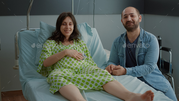 Young happy family expecting childbirth in hospital ward
