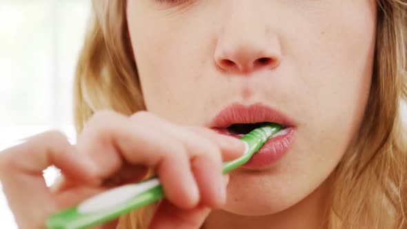 Portrait of woman brushing her teeth in bathroom alt