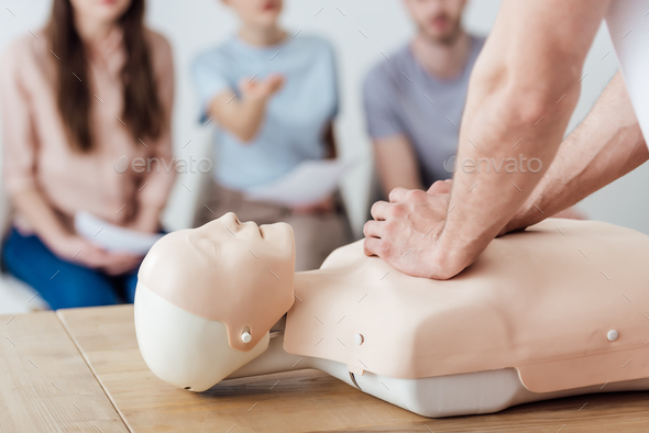 cropped view of instructor performing chest compression on dummy during cpr training class