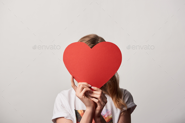 young woman with obscure face and empty paper cut heart card isolated on grey