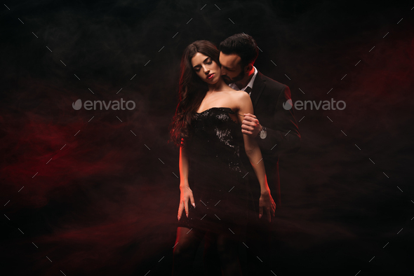 handsome man hugging seductive woman in red smoky room