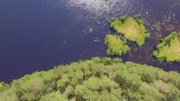 Drone shot of small islands located in a clear Finnish forest lake. alt