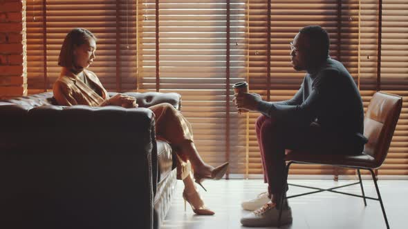 Multiethnic Man and Woman Talking over Coffee in Office alt