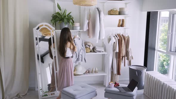 Woman Talks on Phone Choosing Elegant Clothes in Wardrobe
