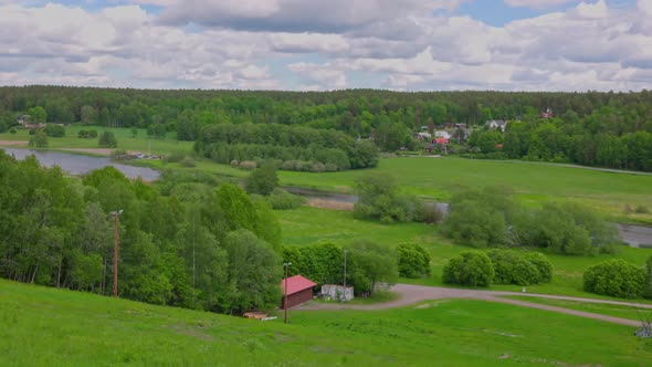 Amazing top view on green fields between green forest trees and flowing river under blue sky. alt