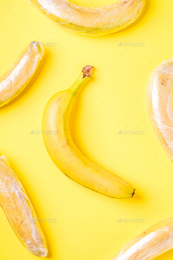 Banana fruits wrapped in stretch wrap plastic on yellow background