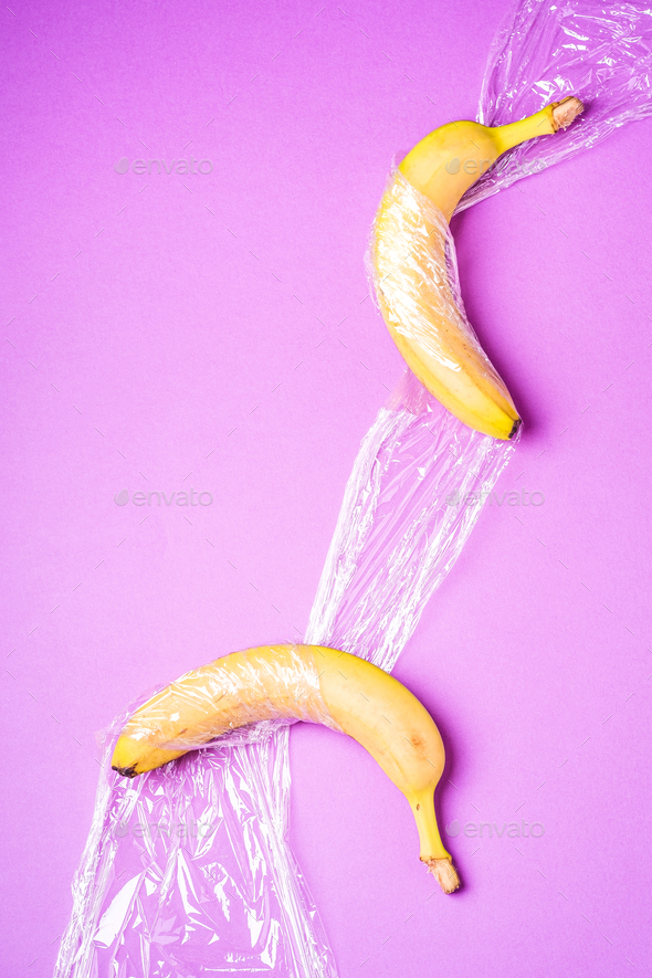 Banana fruit wrapped in stretch wrap plastic on pink background