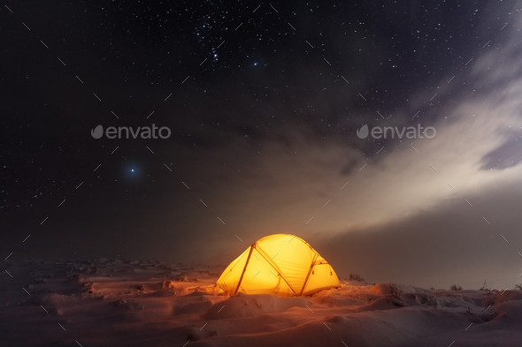 Yellow tent lighted from the inside against the backdrop of glowing city lights - Stock Photo - Images