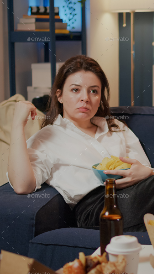 Caucasian adult relaxing on couch with chips as snack