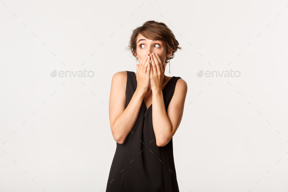Image of impressed and shocked girl gasping, shut mouth with hands and looking left, standing over