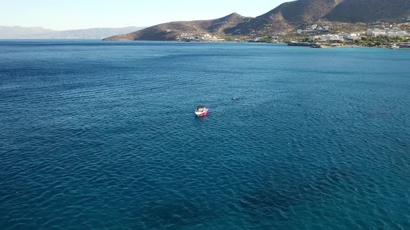 Aerial View of a Speeding Motor Boat in a Deep Blue Colored Sea. Spinalonga Island, Crete, Greece