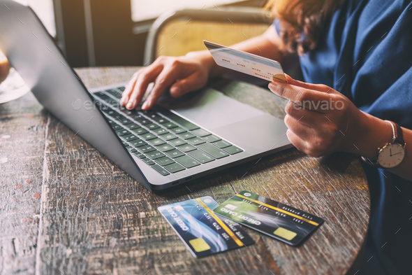 A woman holding credit cards while using laptop computer - Stock Photo - Images