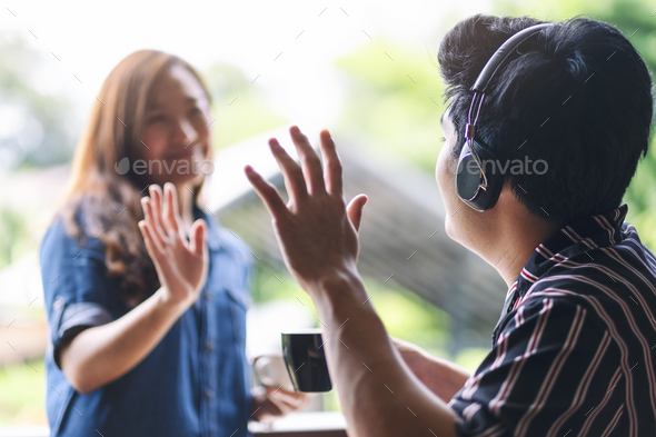 A man greeting and say hi to his female friend while enjoy listening to music with headphone