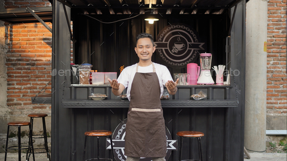 Asian man barista attracts customer's attention in container themed cafe